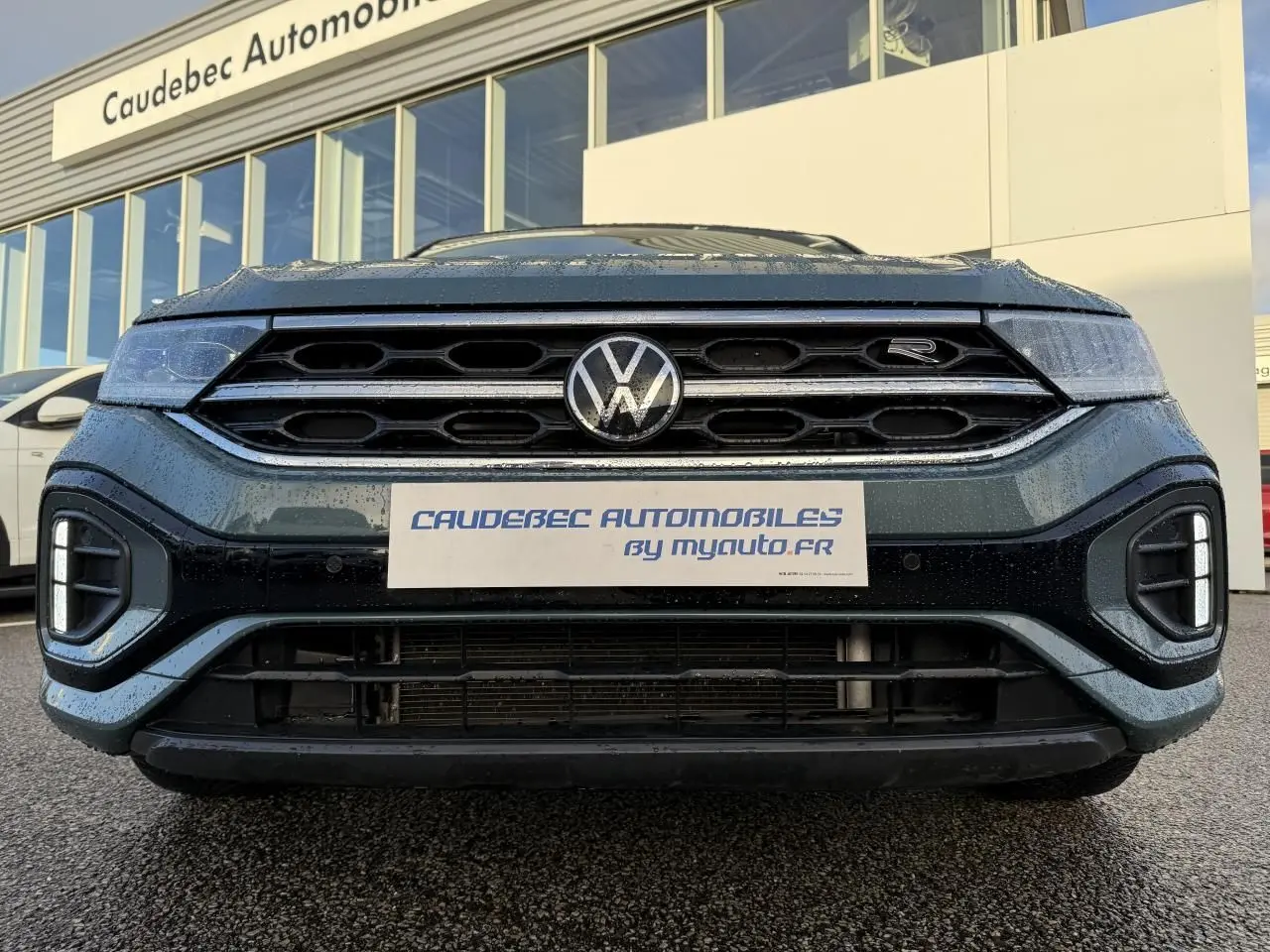 Vue frontale rapprochée du Volkswagen T-Roc bleu avec calandre hexagonale et logo R visible sur la grille.