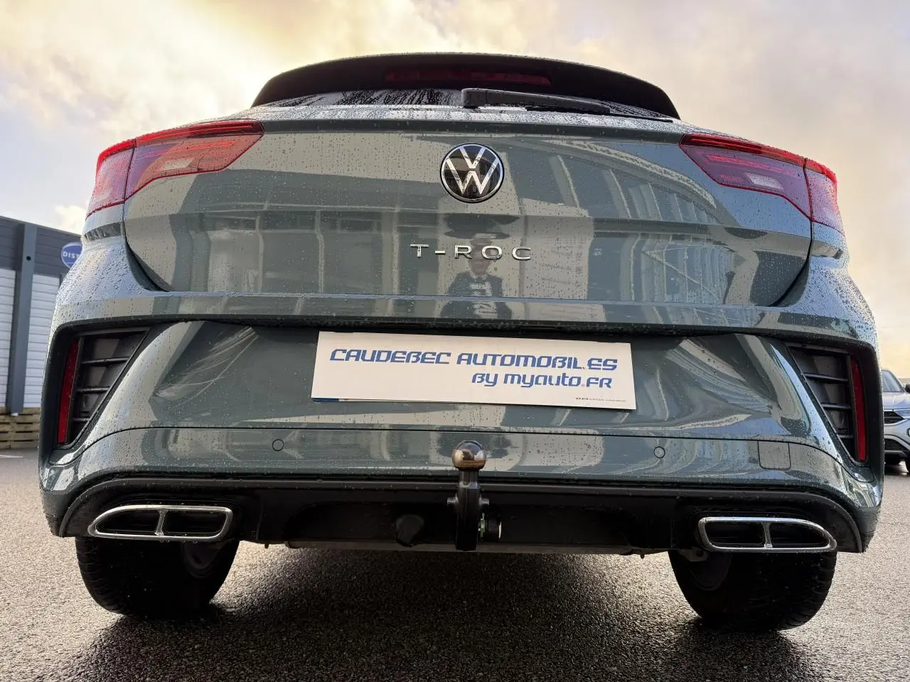 Vue arrière basse d'un Volkswagen T-Roc bleu avec attelage amovible et double sortie d'échappement chromée.