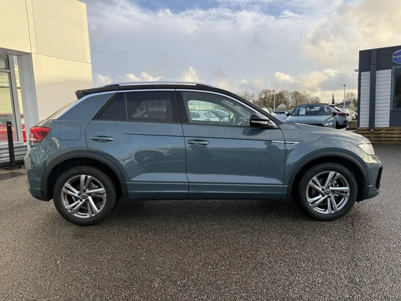 Profil côté gauche d'un Volkswagen T-Roc bleu 2025 avec jantes alliage 17 pouces et toit noir.