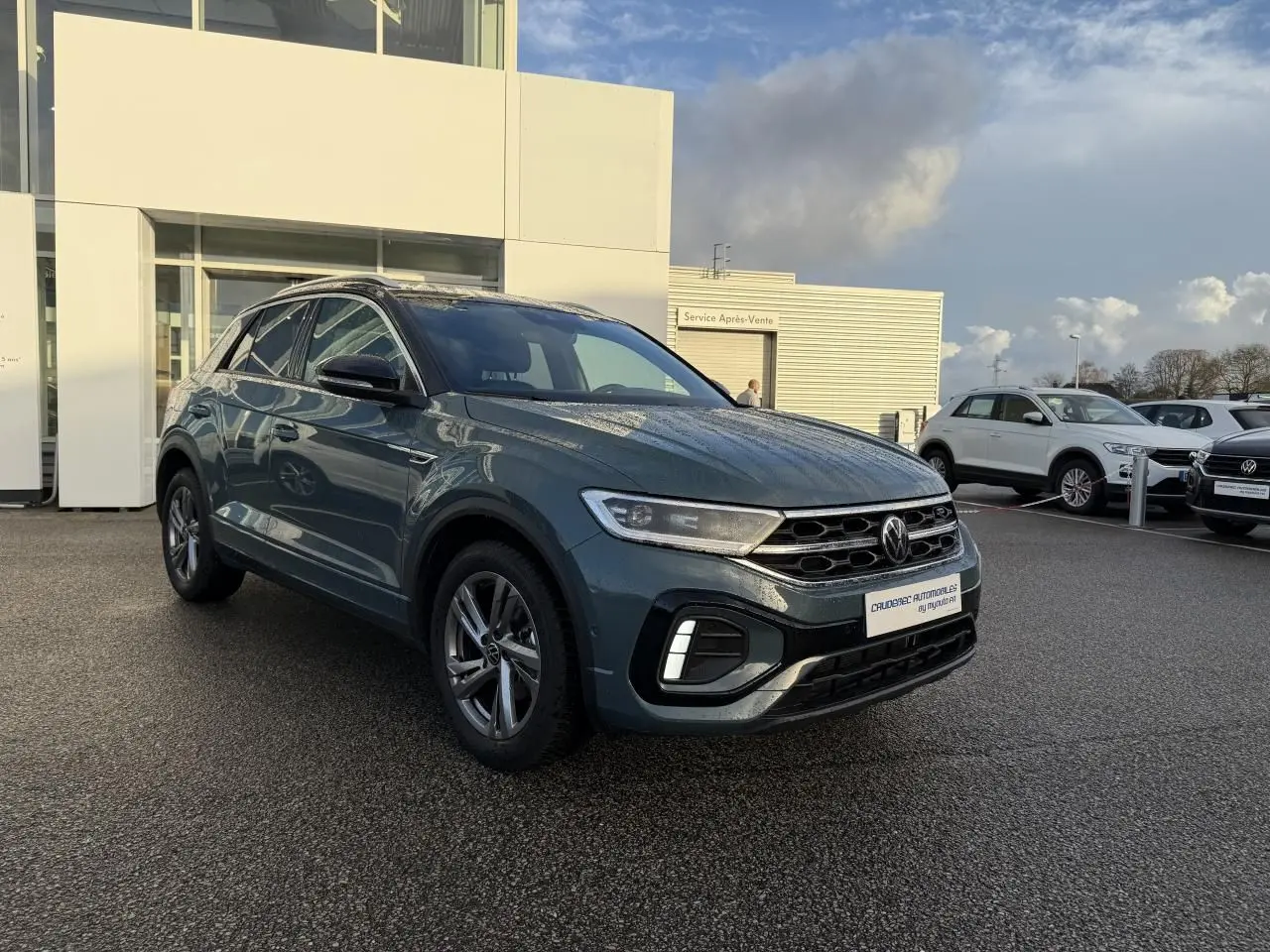 Volkswagen T-Roc bleu en vue 3/4 avant droit, avec jantes alliage et calandre noire brillante.