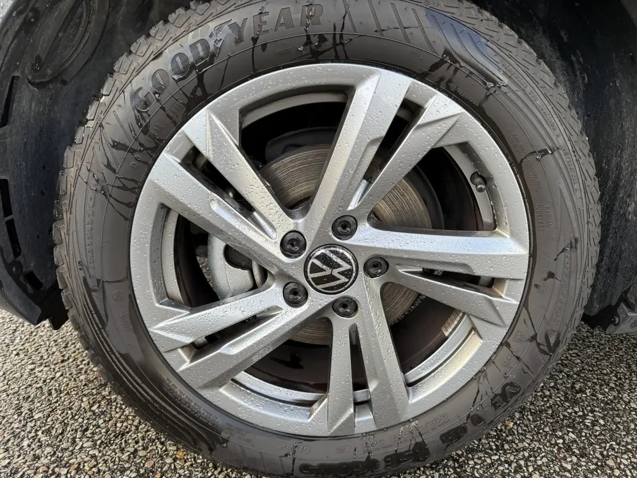 Gros plan sur une jante en alliage léger gris galvanisé de 17 pouces avec logo Volkswagen au centre, pneu Goodyear humide.