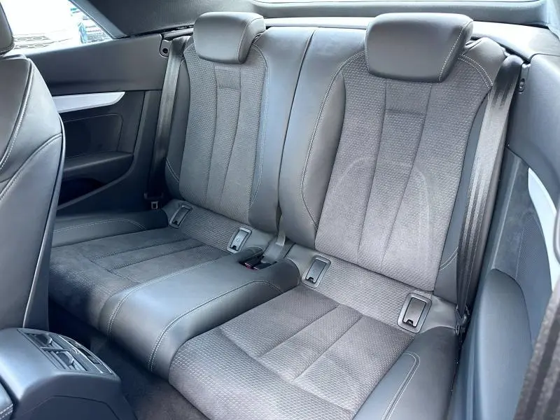 Vue rapprochée des sièges arrière en cuir noir de l'Audi A5 Cabriolet 35 TFSI 2023 avec capote noire.