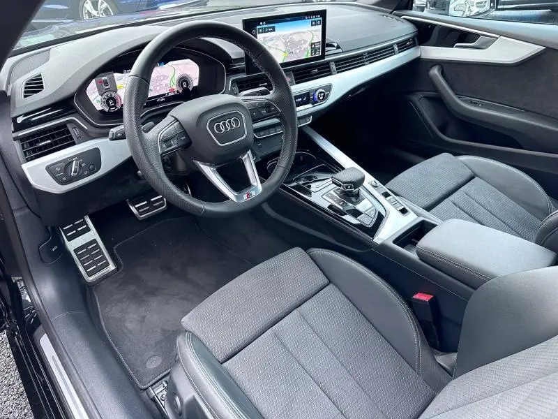 Vue intérieure côté conducteur de l'Audi A5 Cabriolet 35 TFSI 150 S tronic 7 Avus 2023 avec volant cuir multifonction et écran tactile.