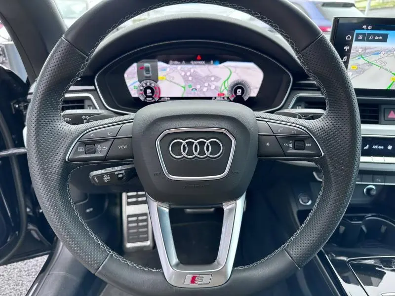 Volant cuir perforé Audi A5 Cabriolet 35 TFSI 2023 avec commandes multifonctions et tableau de bord numérique affichant la navigation.
