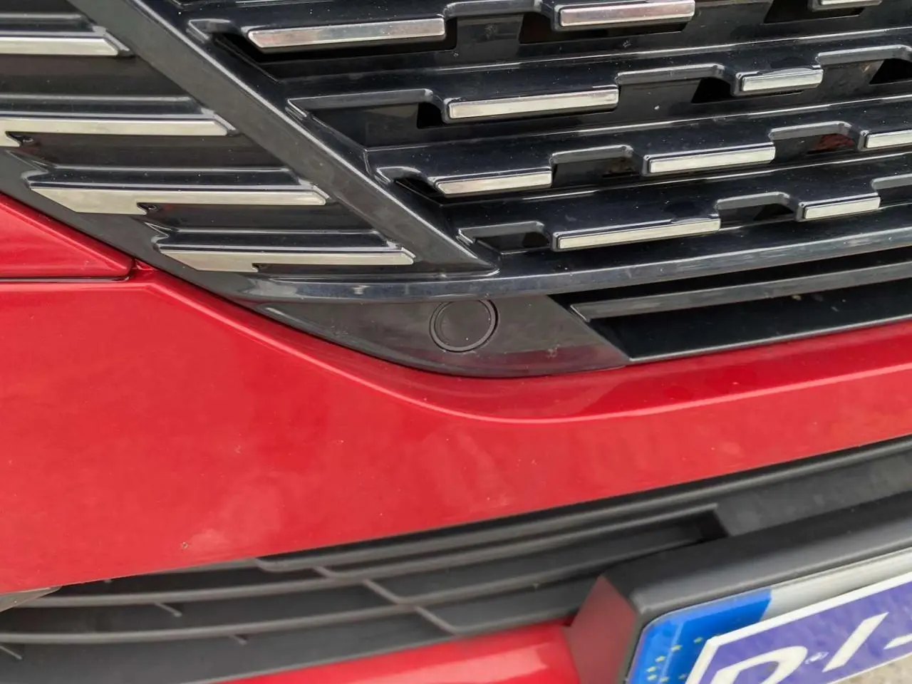 Gros plan sur la calandre avant rouge Elixir de la Peugeot 308 GT 2022 avec capteur de caméra 360° intégré.