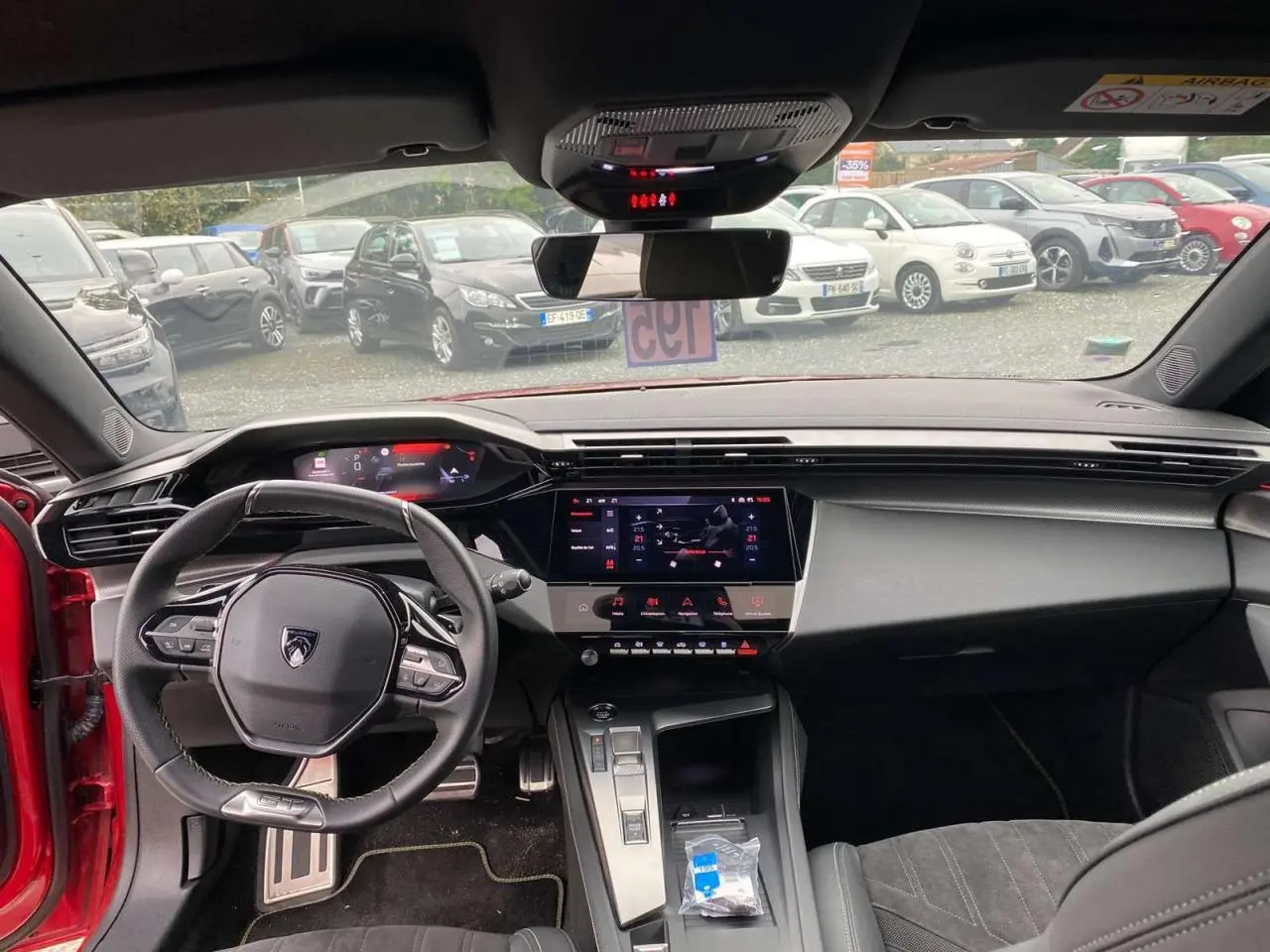 Vue intérieure avant de la Peugeot 308 rouge Elixir 2022, avec tableau de bord numérique et écran tactile central.