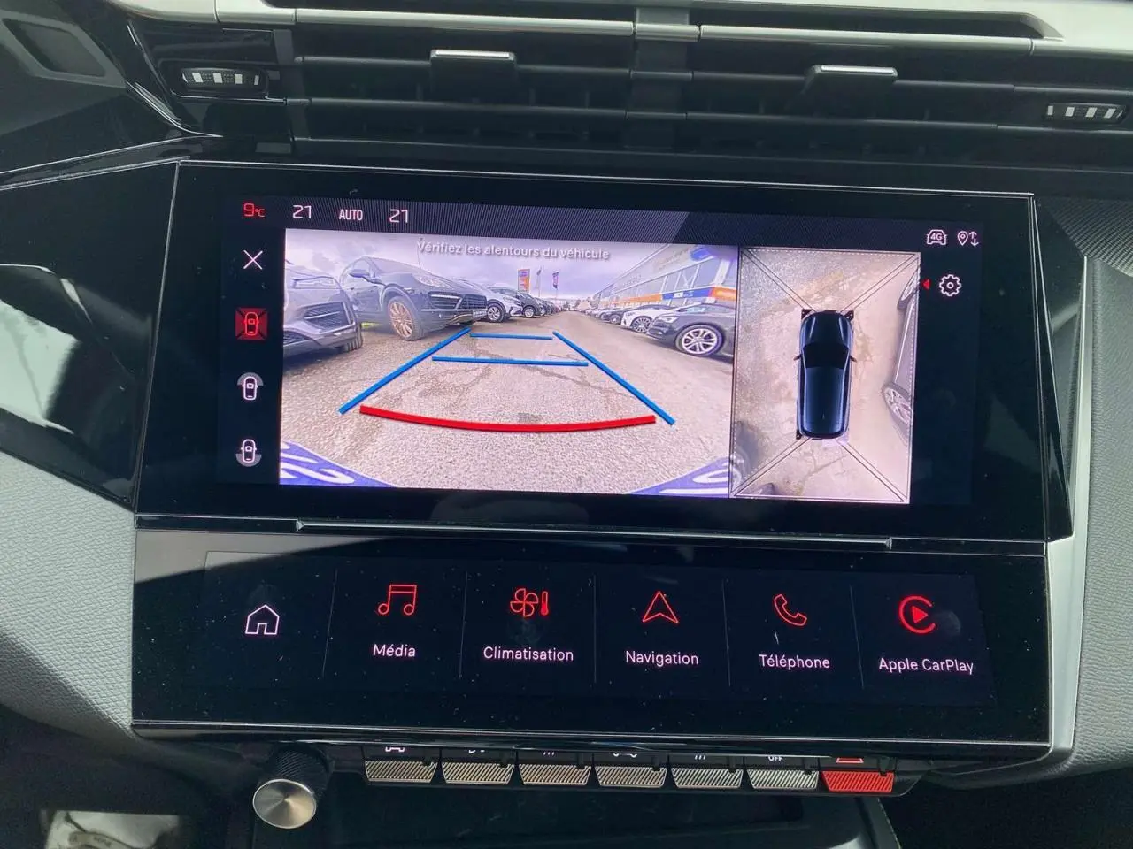 Écran central tactile montrant la caméra 360° avec vue arrière et dessus d'une Peugeot 308 rouge Elixir.