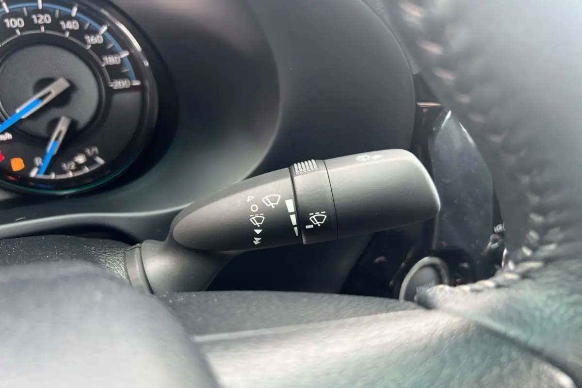Gros plan sur la commande d’essuie-glace à gauche du volant dans le tableau de bord noir du Toyota Hilux 2025.