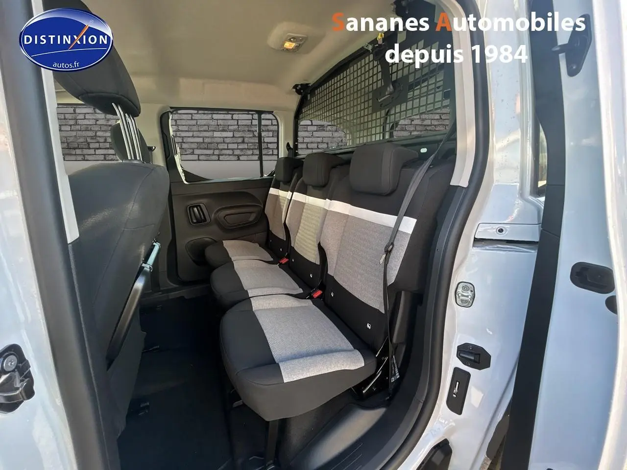Vue latérale droite sur les sièges arrière gris et noirs du Citroën Berlingo blanc avec porte ouverte.