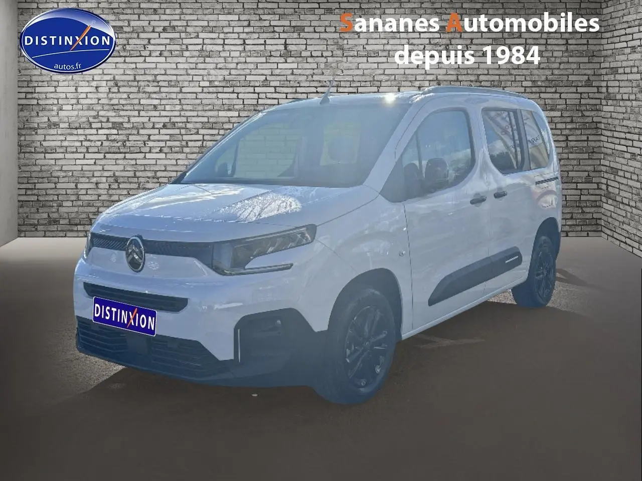 Vue 3/4 avant droit d'un Citroën Berlingo blanc avec barres de toit noires et jantes alliage sombres.