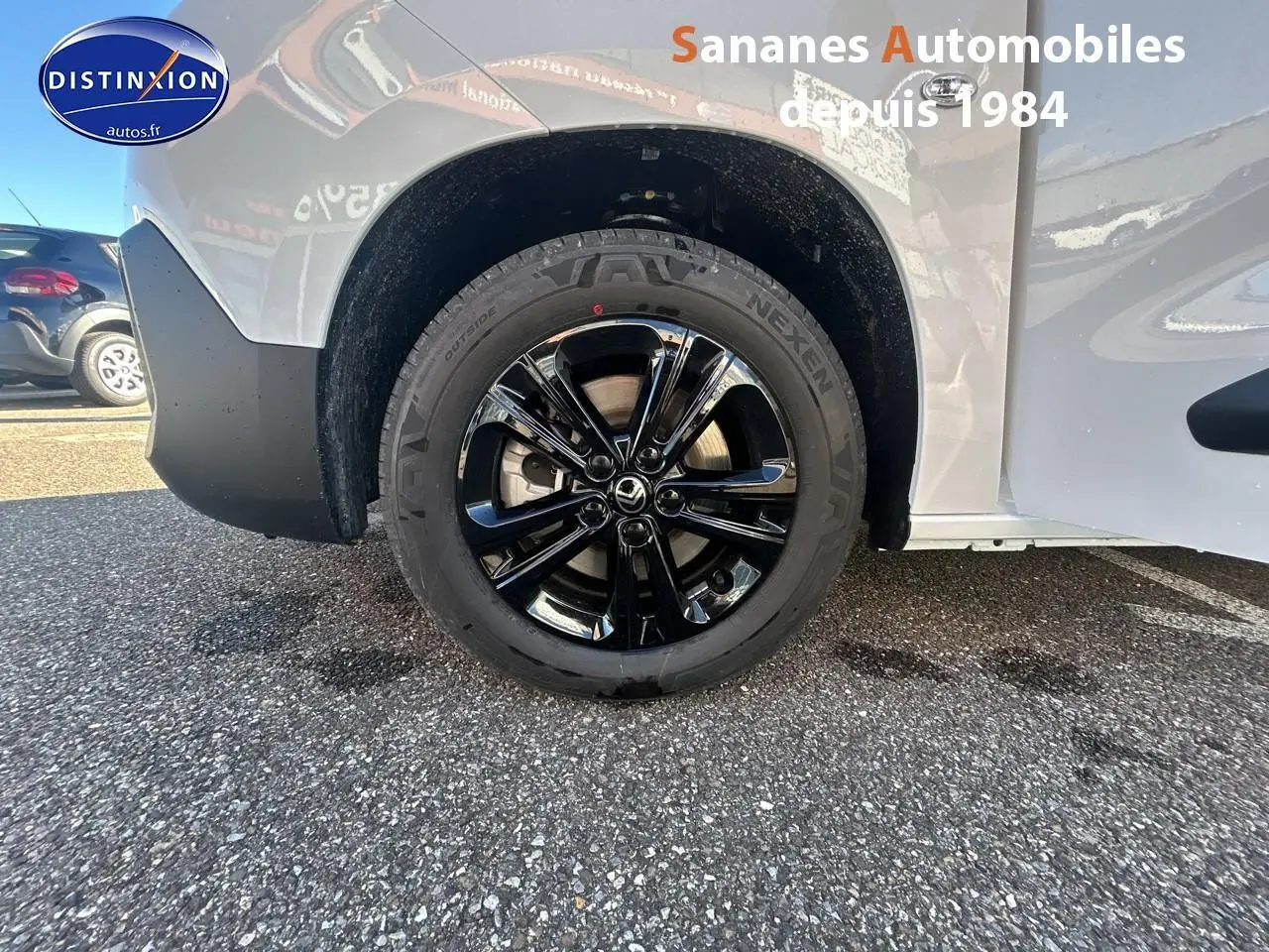 Gros plan sur la roue arrière droite noire brillante du Citroën Berlingo blanc, avec partie de la carrosserie visible.