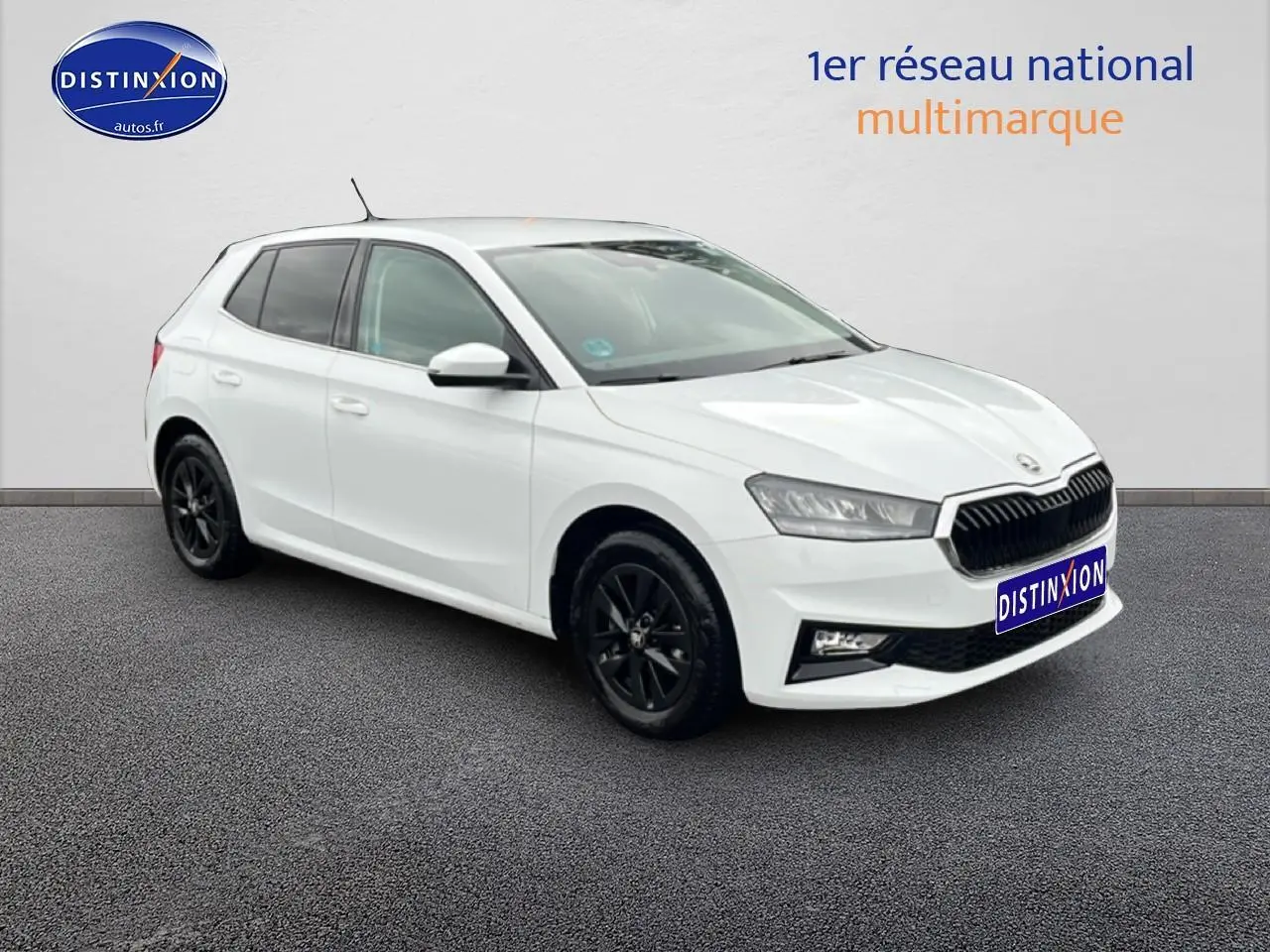 Vue 3/4 avant droite d'une Skoda Fabia blanche avec jantes noires sur fond neutre.