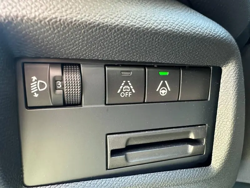 Gros plan sur les commandes de réglage des phares et d’aide à la conduite du Citroën C5 Aircross noir, vue intérieure côté gauche.
