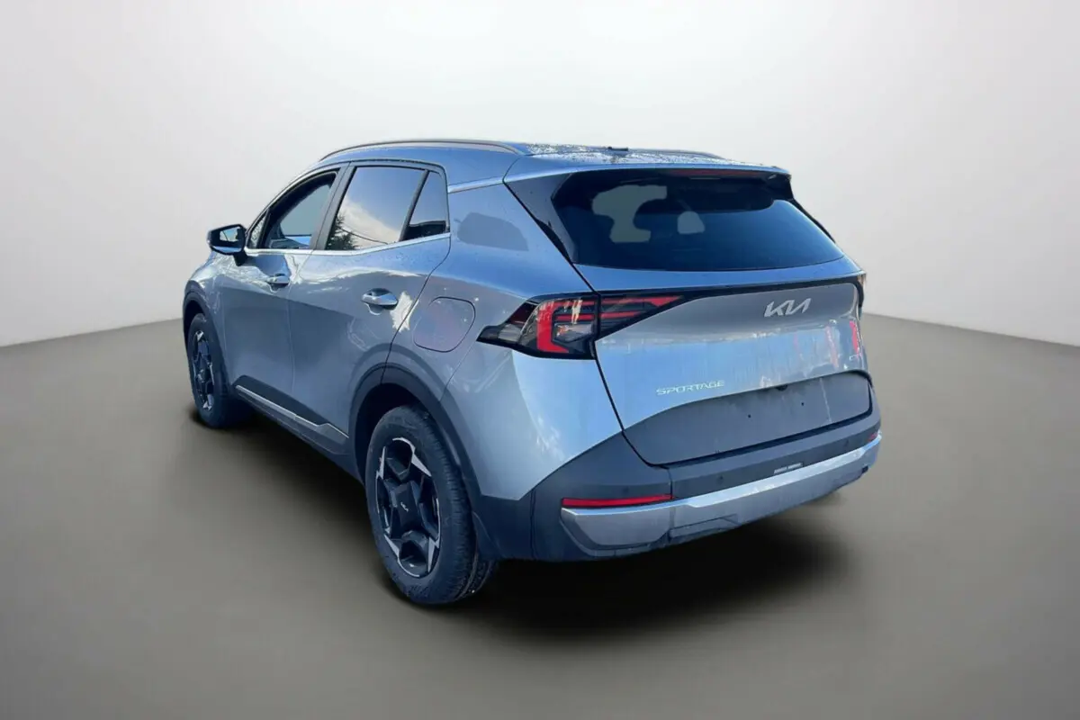 Vue 3/4 arrière gauche d'un Kia Sportage gris perle avec vitres surteintées et jantes alu 18 pouces.