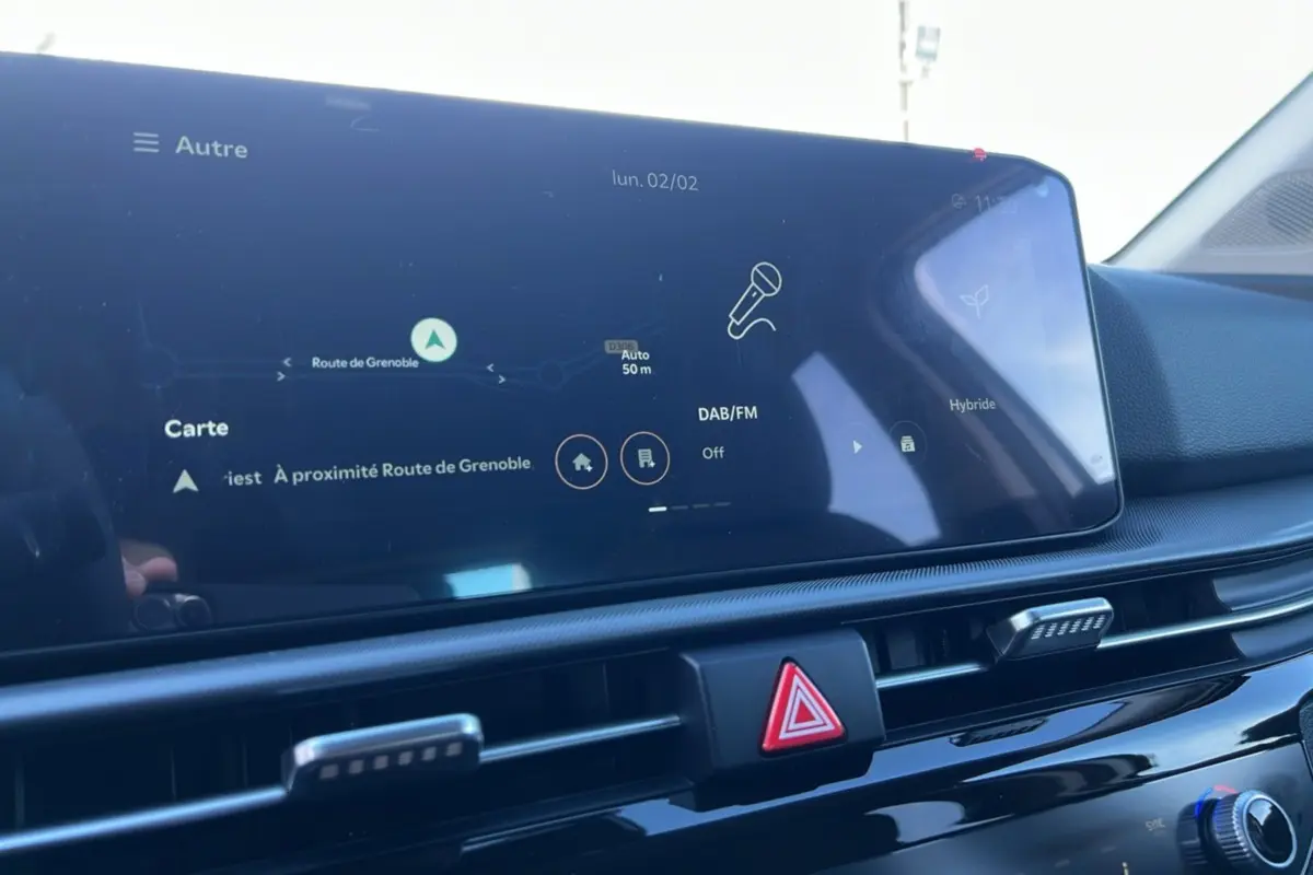 Vue rapprochée de l'écran tactile central et des commandes de ventilation du tableau de bord du Kia Sportage gris perle 2026.