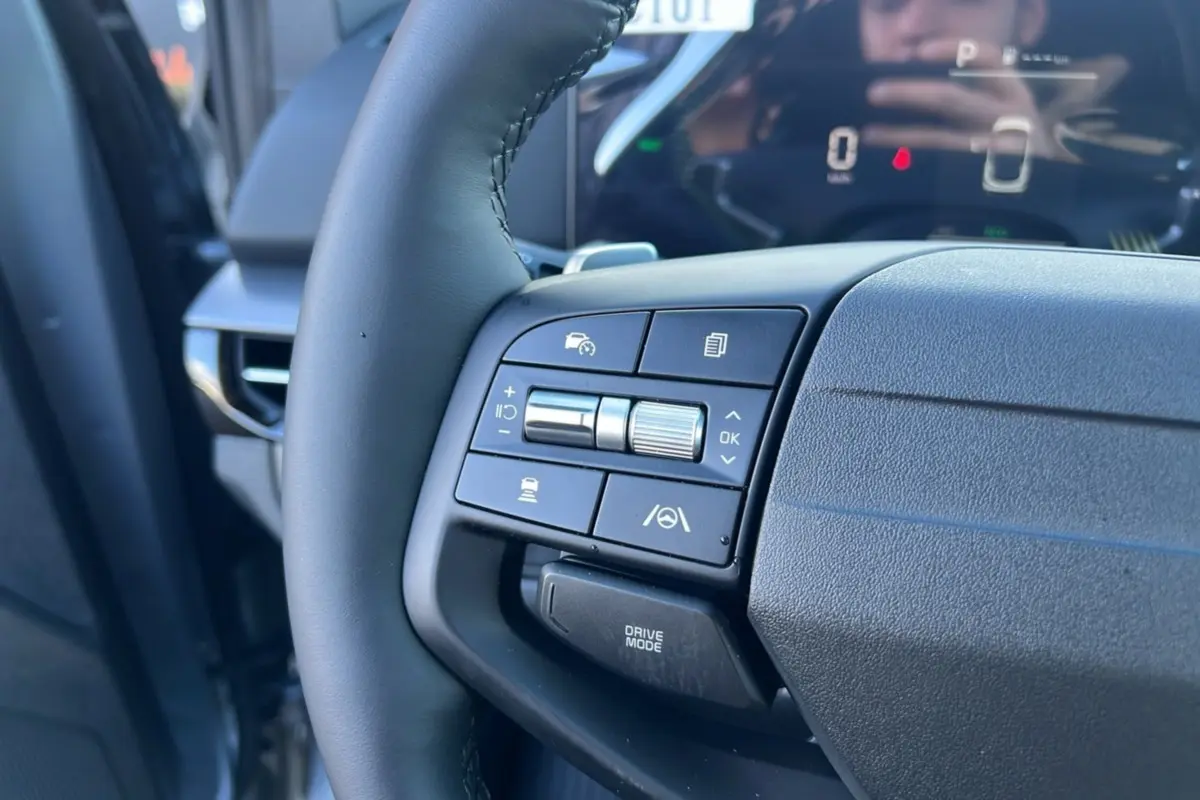 Gros plan sur le volant cuir multifonctions du Kia Sportage 2026 gris perle, avec commandes d’aide à la conduite visibles.