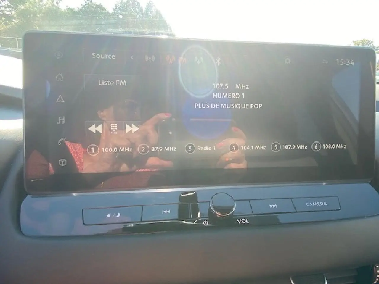 Écran tactile multimédia du Nissan Qashqai 2023 affichant la liste FM avec commandes volume et caméra.