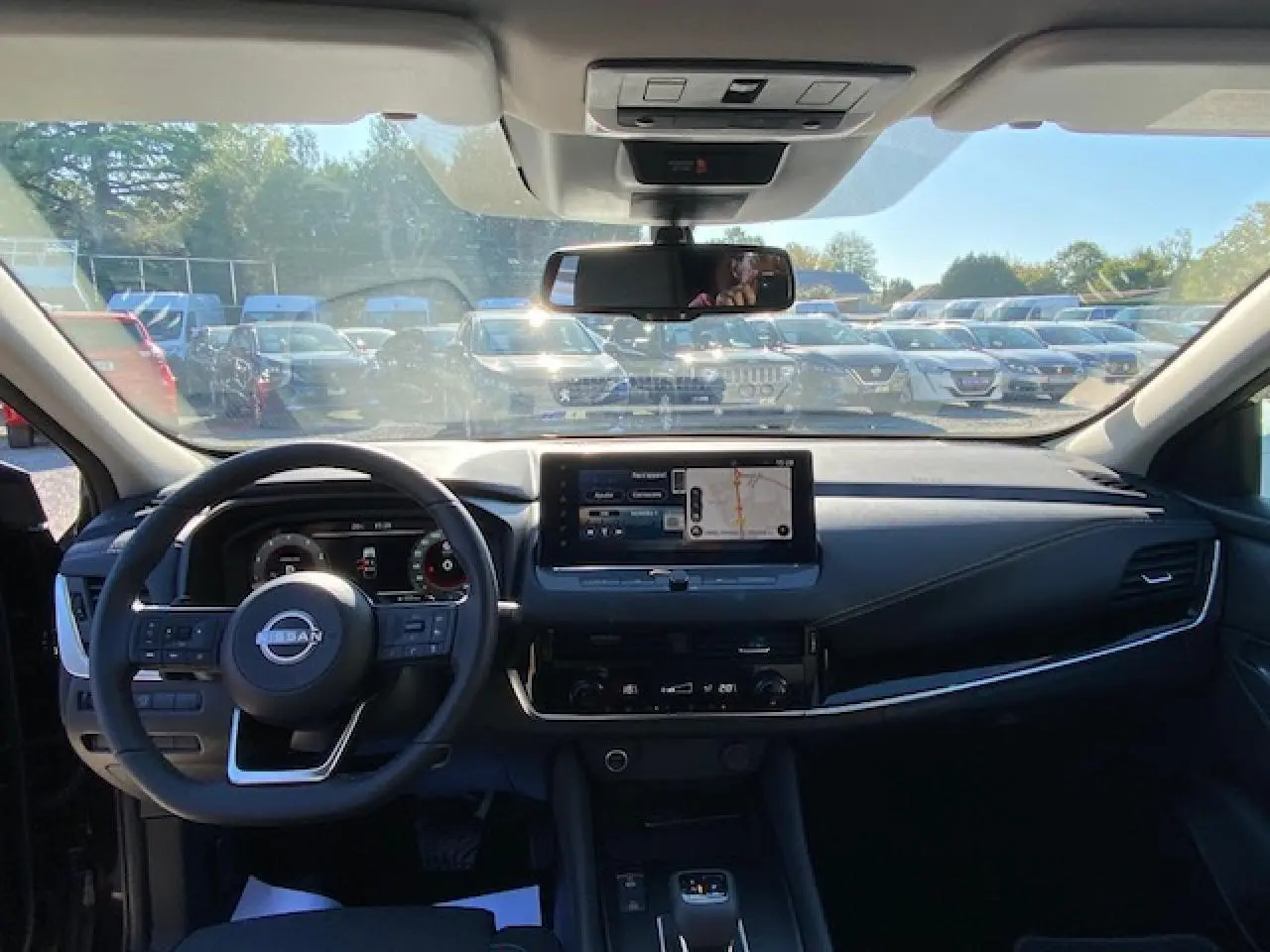 Vue intérieure du tableau de bord noir du Nissan Qashqai 2023, avec écran tactile central et volant multifonction.