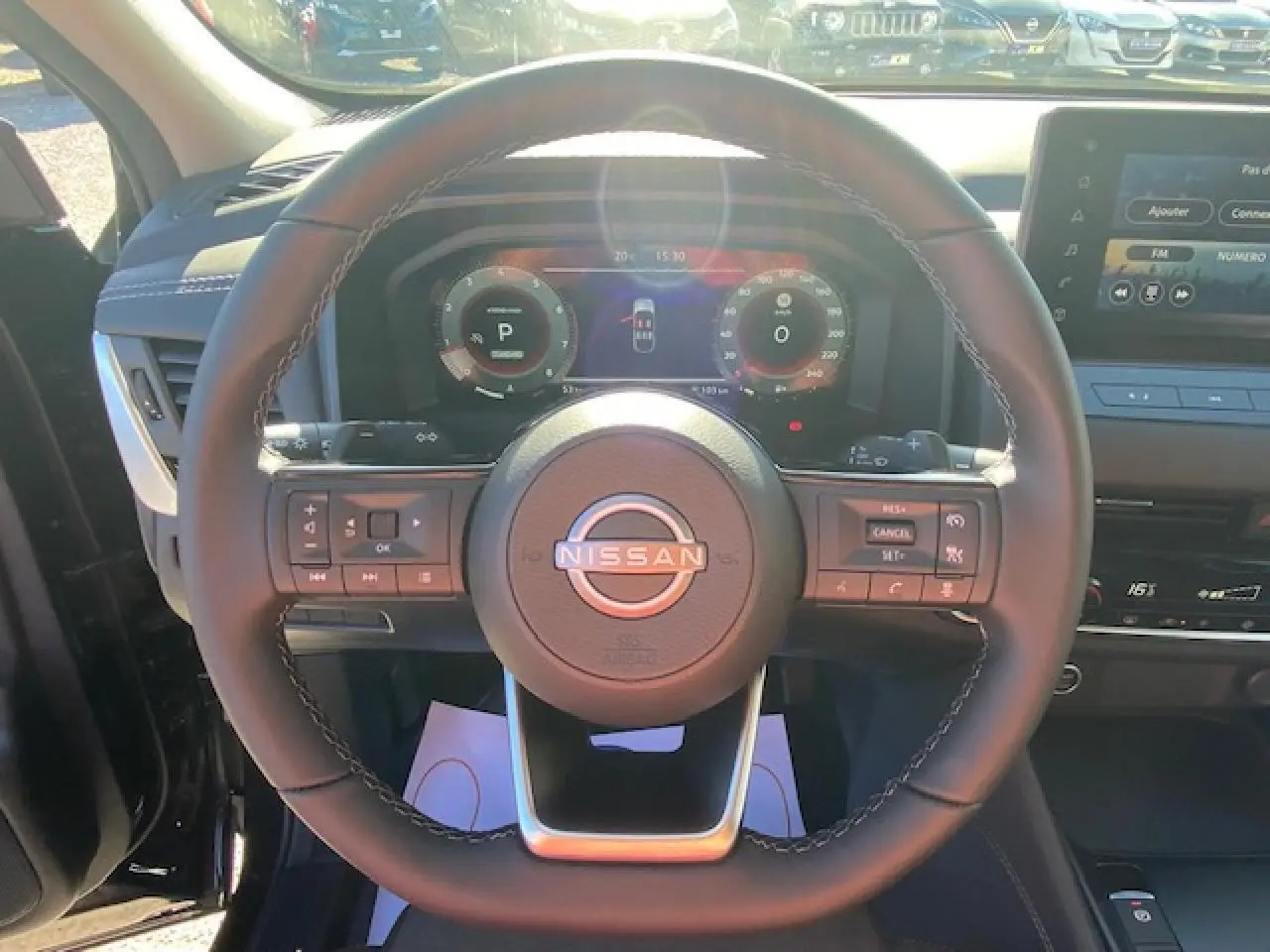 Vue intérieure centrée sur le volant noir du Nissan Qashqai 2023 avec tableau de bord numérique et commandes intégrées.