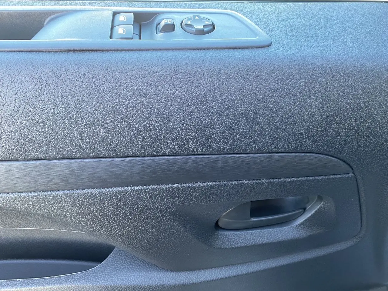 Gros plan sur la porte intérieure côté conducteur du Peugeot Expert blanc, avec commandes de vitres et poignée noire.