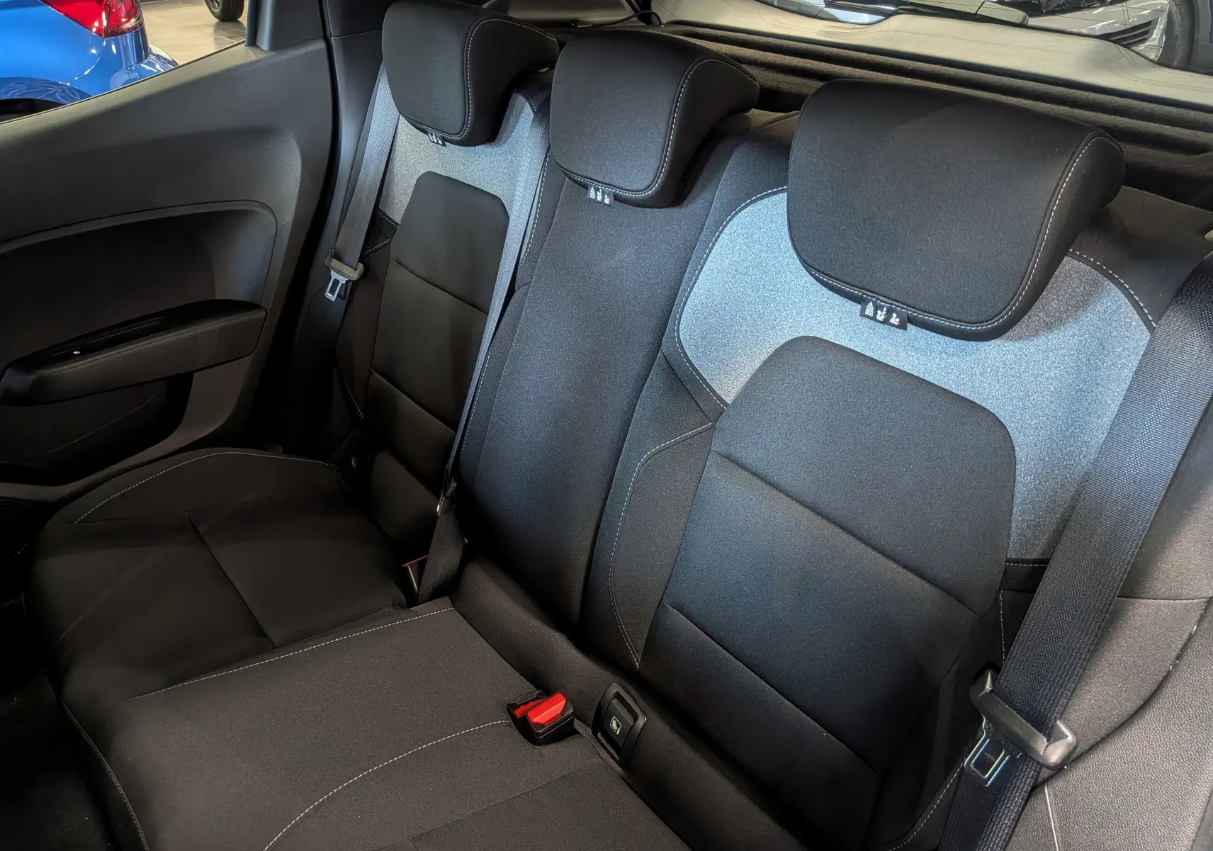 Vue intérieure sur les sièges arrière en tissu noir et gris de la Renault Clio V 2025, avec ceintures de sécurité visibles.