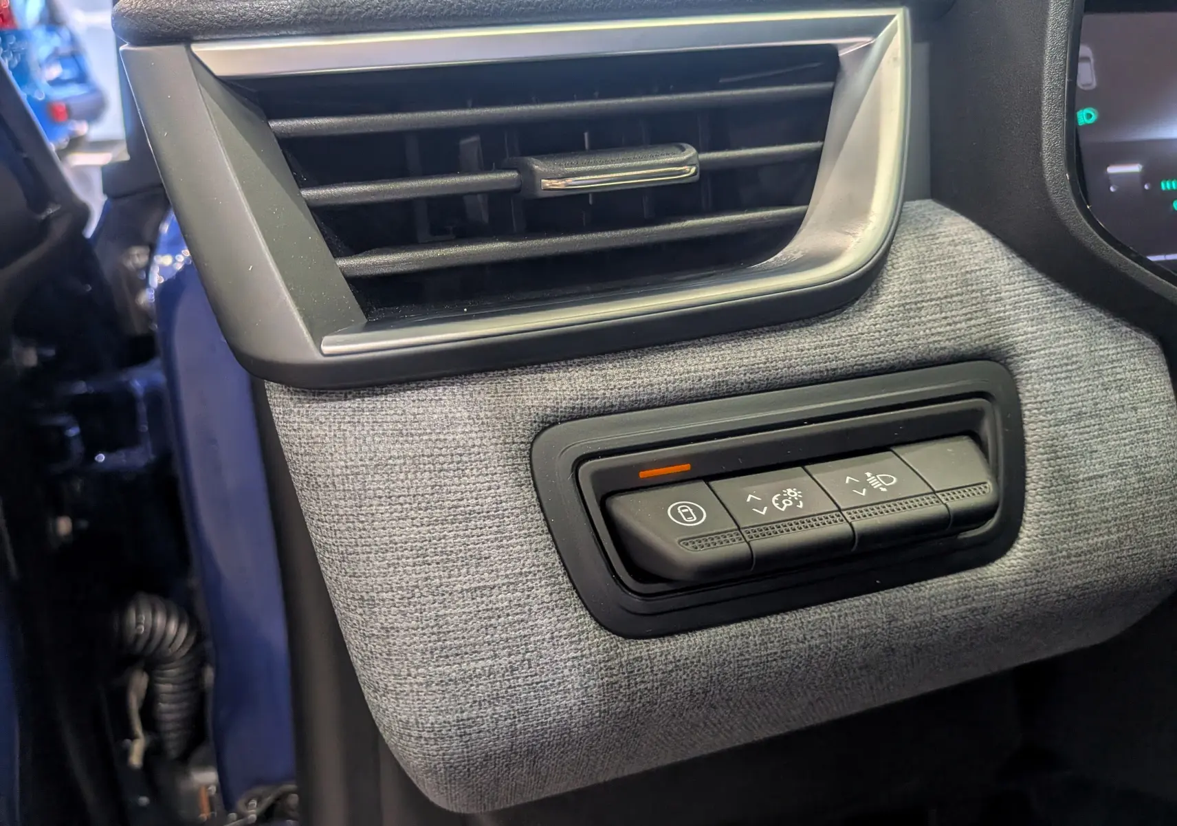 Détail du tableau de bord côté gauche avec grille d’aération et commandes d’éclairage sur tissu gris dans Renault Clio V Bleu Iron.