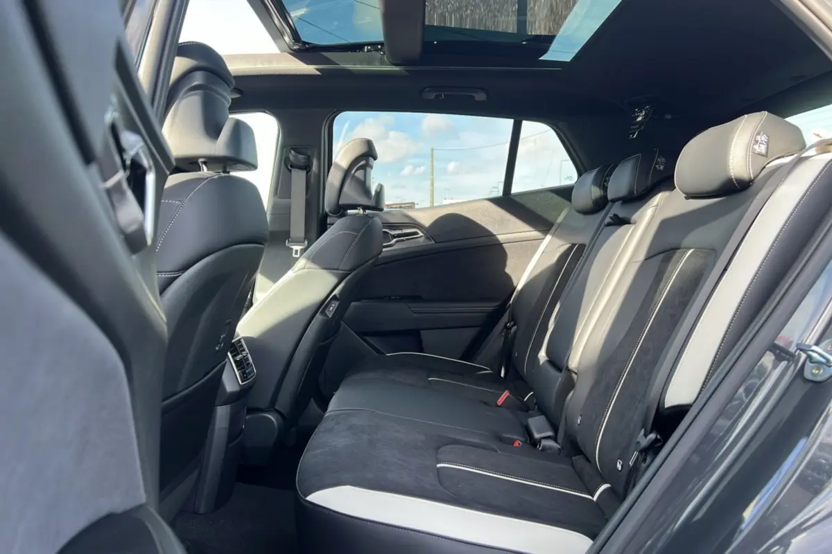 Vue intérieure de la banquette arrière du Kia Sportage gris eclipse avec toit panoramique et sièges en cuir noir et alcantara.