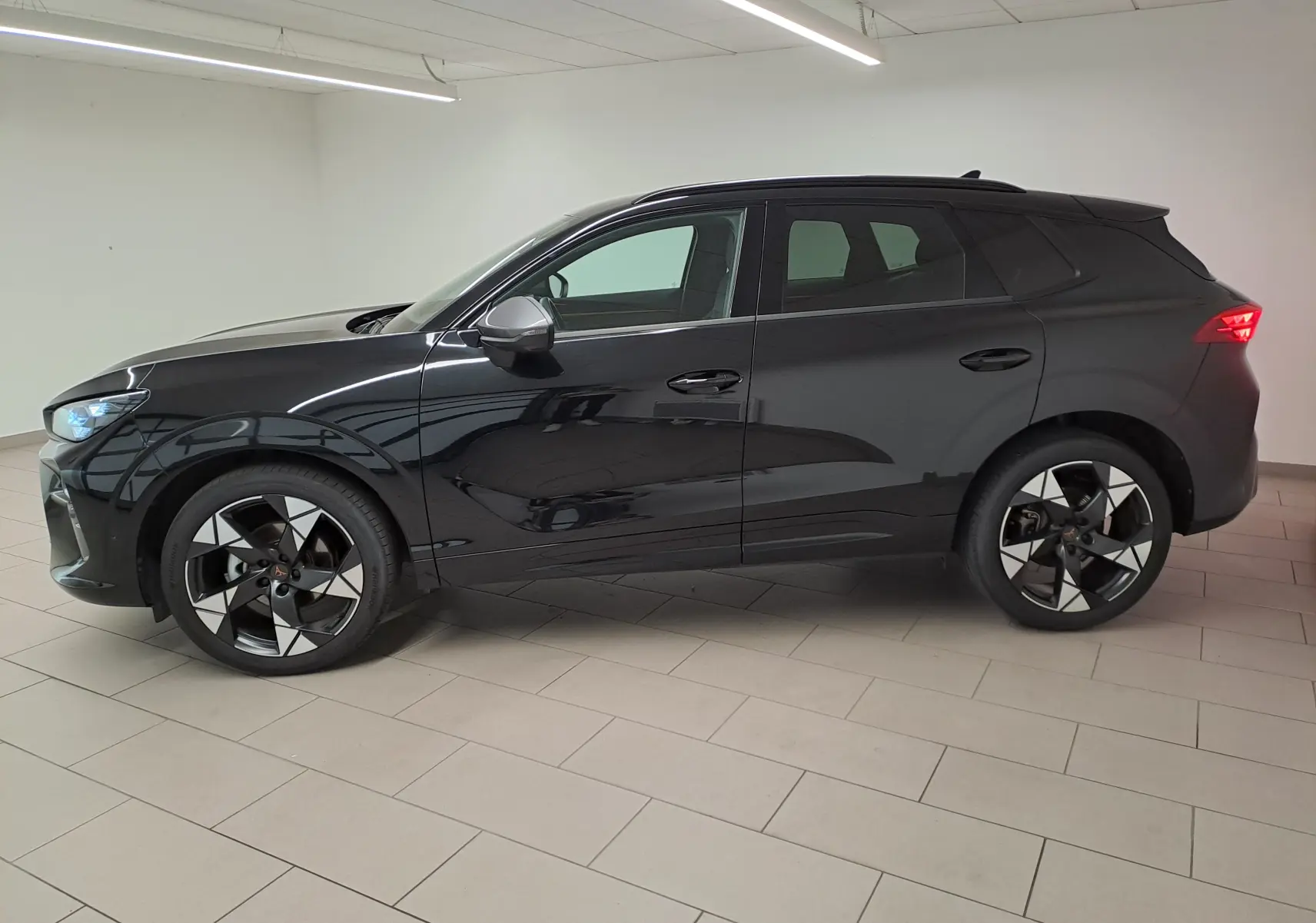 Vue de profil côté gauche du CUPRA TERRAMAR 2025 noir minuit avec jantes 20'' Gravity usinées dans un intérieur lumineux.