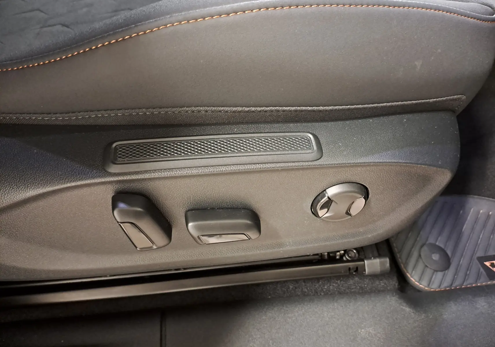 Détail des commandes de réglage électrique du siège conducteur du CUPRA TERRAMAR 2025 en tissu noir avec surpiqûres orange.
