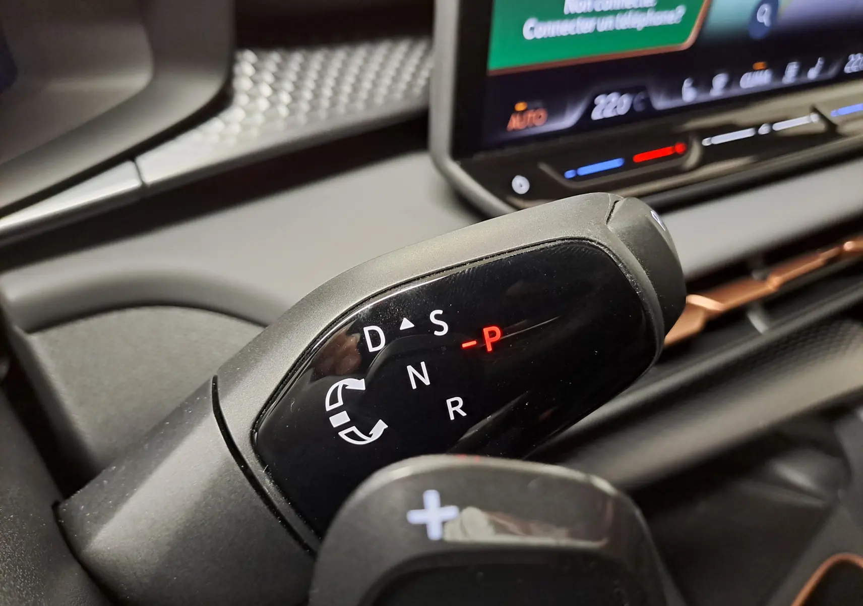 Gros plan sur le sélecteur de boîte automatique noir du CUPRA TERRAMAR 2025 avec écran tactile en arrière-plan.
