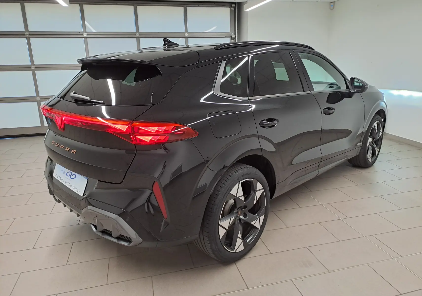 Vue 3/4 arrière droite du CUPRA TERRAMAR noir minuit avec feux arrière allumés et jantes 20'' Gravity usinées.