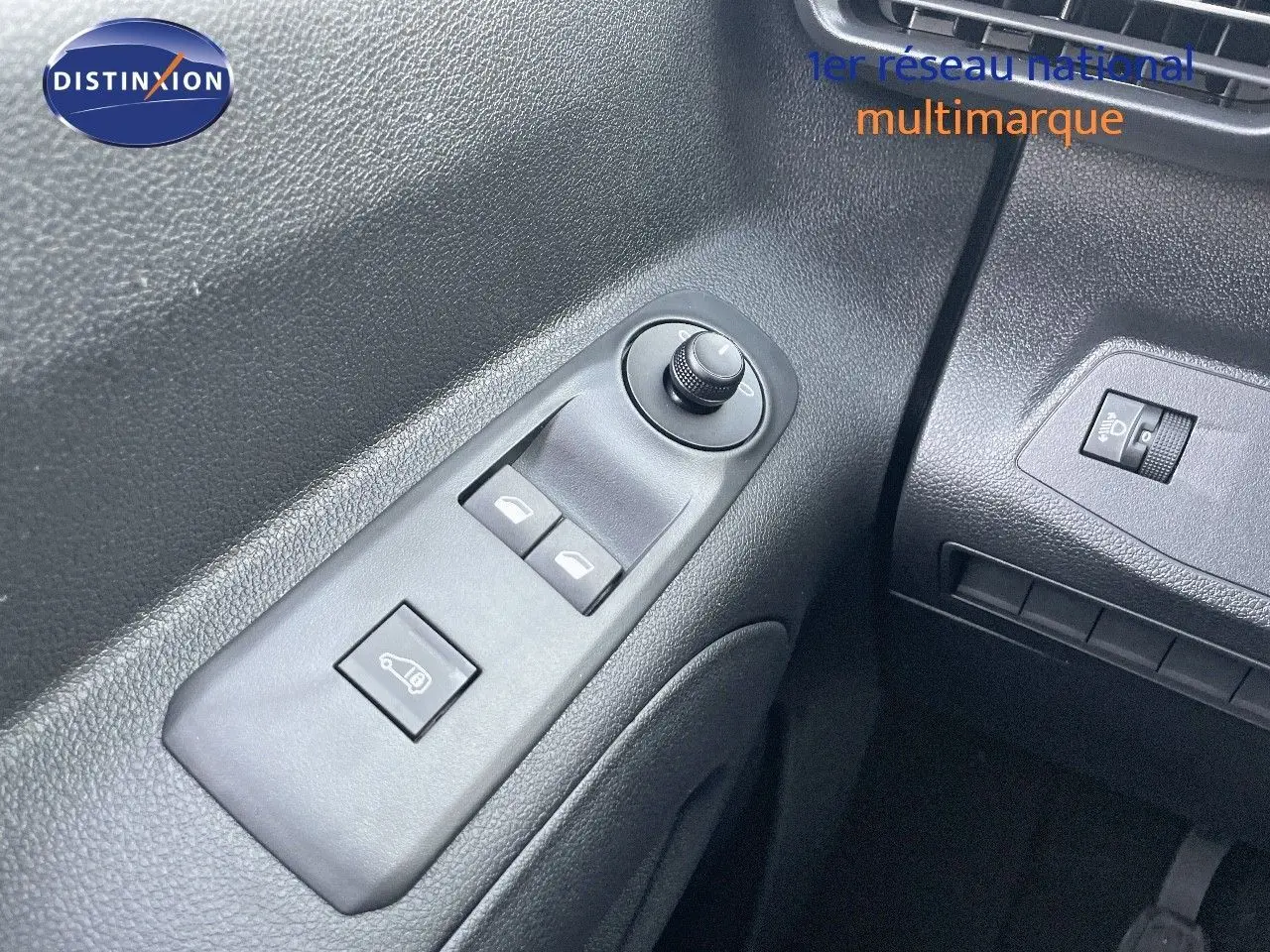 Gros plan sur les commandes de lève-vitres et réglage des rétroviseurs côté gauche du Peugeot Partner 2025, intérieur noir.