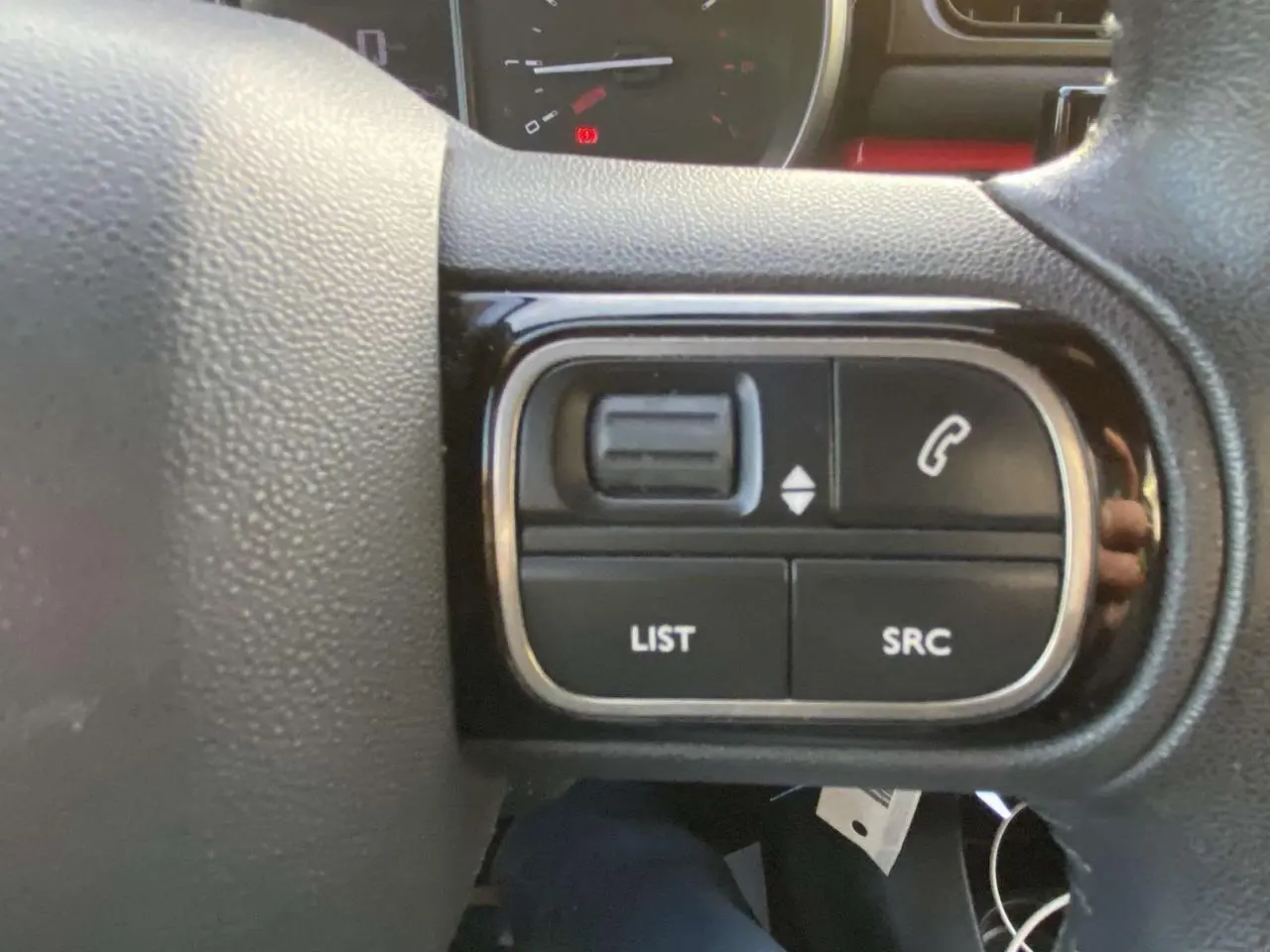 Gros plan sur les commandes audio au volant d'une Citroën C3 noire toit rouge, version Shine 2017.