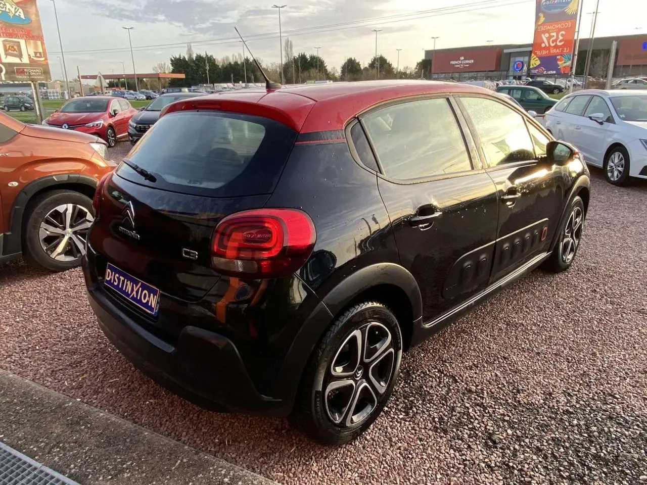 Vue 3/4 arrière droite d'une Citroën C3 noire avec toit rouge et protections latérales Airbump visibles.