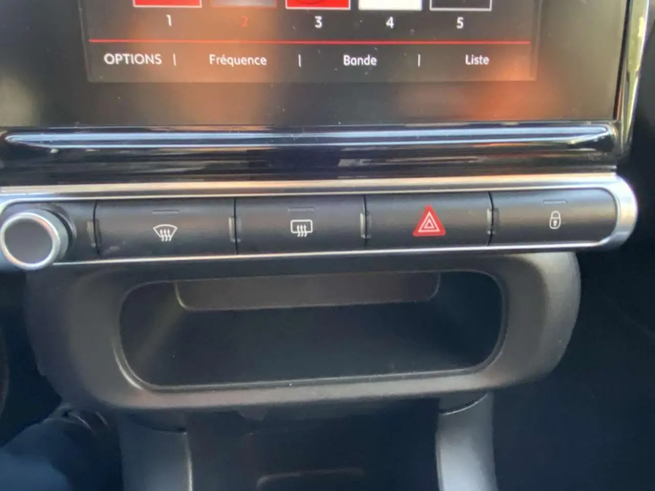 Boutons de commande de la console centrale de la Citroën C3 2017 noire avec toit rouge, incluant les feux de détresse et verrouillage.