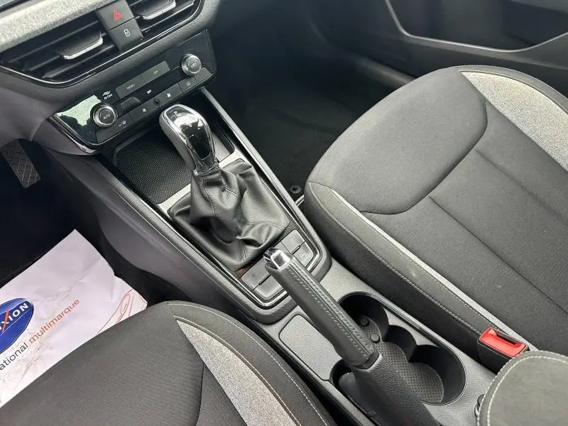 Vue rapprochée de la console centrale intérieure de la Skoda Scala blanche, avec levier de vitesse automatique et sièges tissu noir/gris.