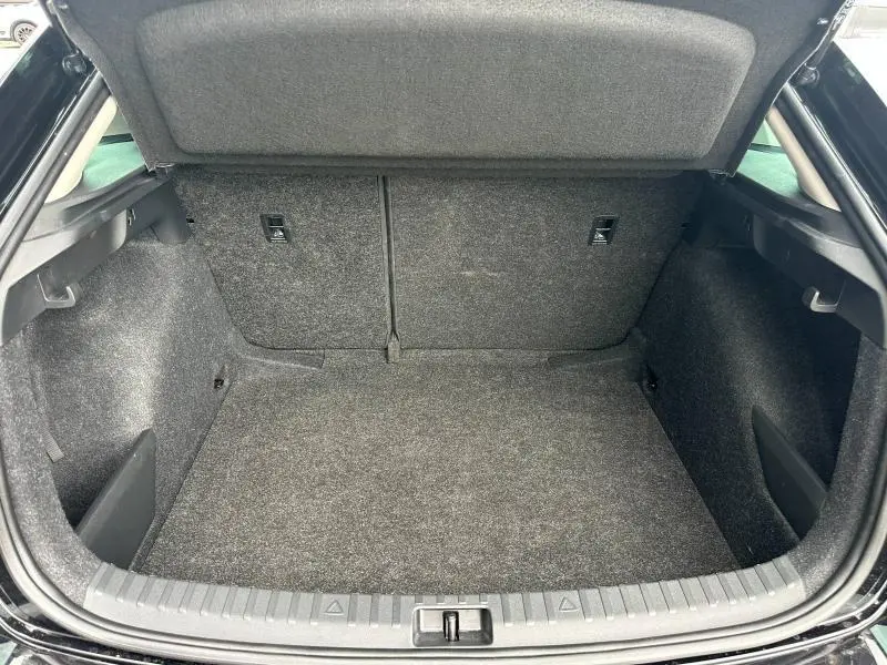 Vue intérieure du coffre spacieux et tapissé de tissu gris foncé d'une Skoda Scala 2025, version essence blanc cristal.