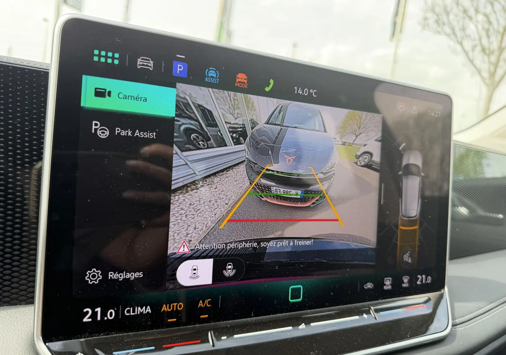 Écran tactile intérieur montrant la caméra de recul avec vue frontale d'une voiture noire en stationnement.