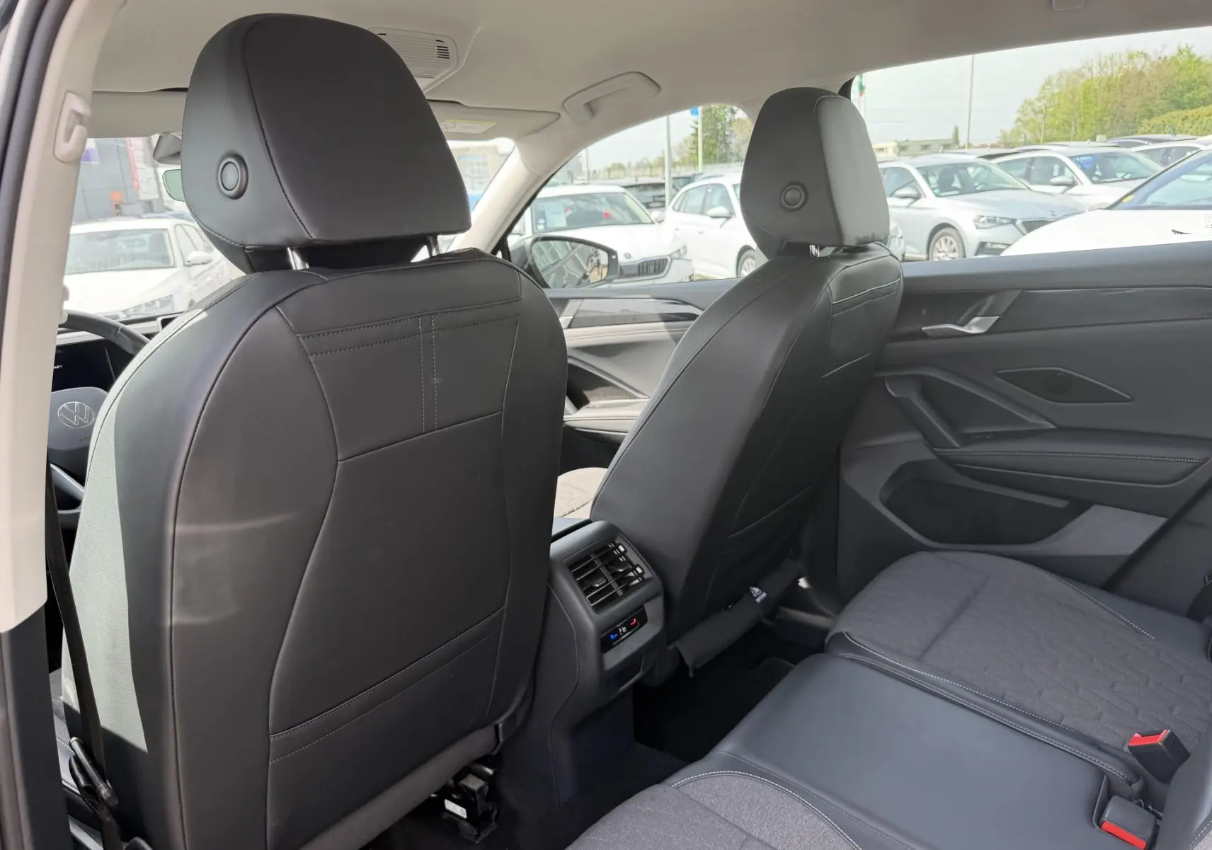 Vue arrière intérieure du Volkswagen Tiguan 2025 avec sièges noirs en cuir et tissu, et commandes de climatisation arrière visibles.