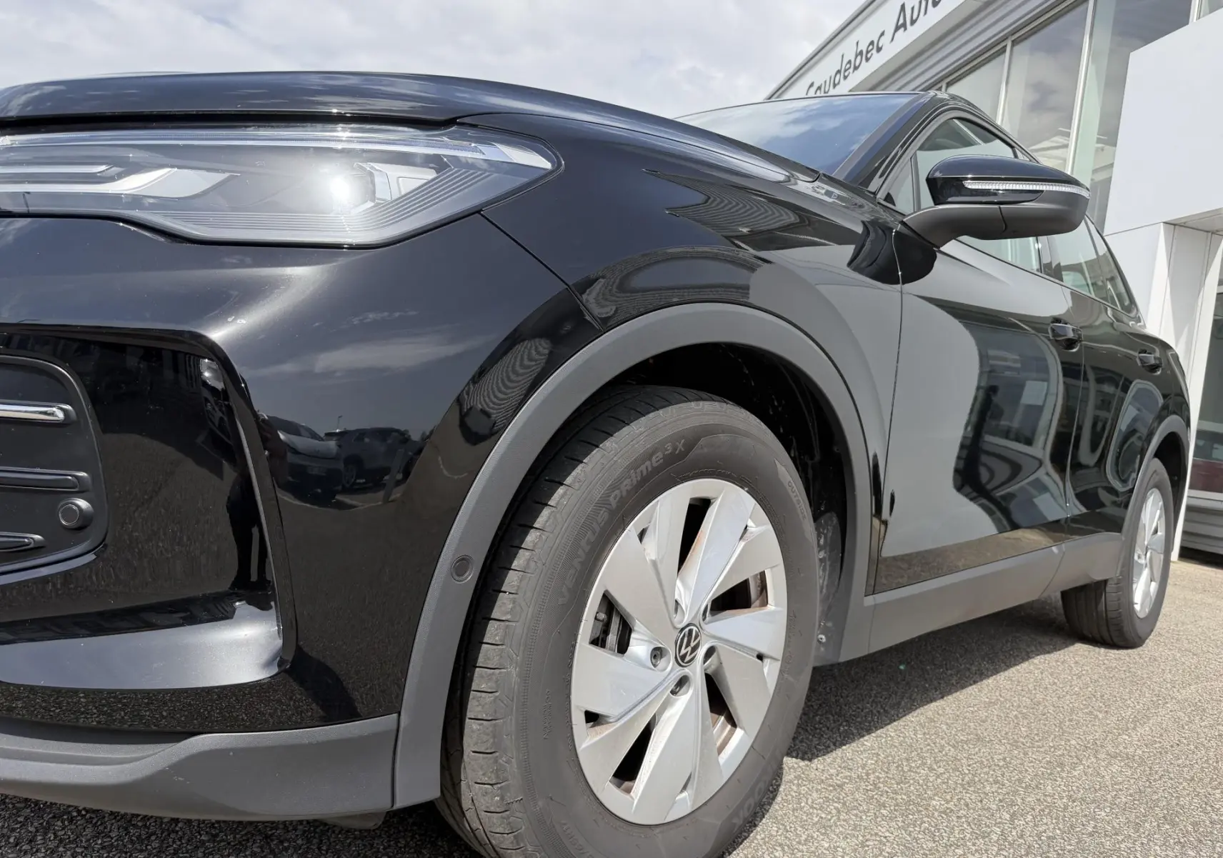 Vue 3/4 avant droit d'un Volkswagen Tiguan noir mettant en valeur le projecteur LED et la jante alliage 17 pouces.