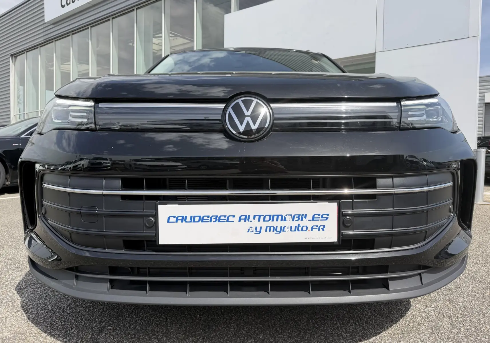 Vue frontale rapprochée du Volkswagen Tiguan 2025 noir avec calandre épurée et logo VW central lumineux.