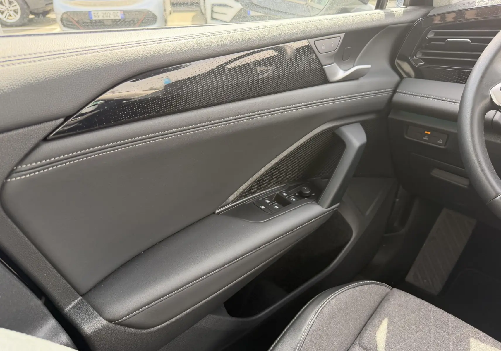 Vue intérieure côté gauche du Volkswagen Tiguan 2025, porte avec garniture noire et commandes électriques des vitres.