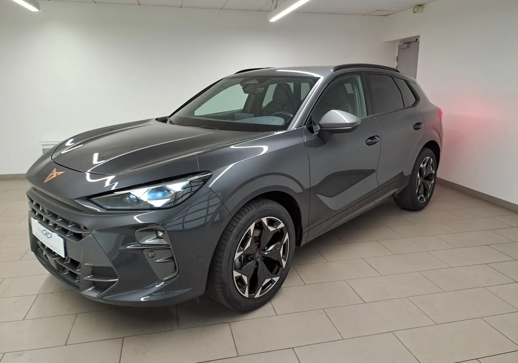 Vue 3/4 avant du CUPRA TERRAMAR gris Timanfaya avec jantes 19'' Cosmic usinées et feux LED allumés en intérieur.