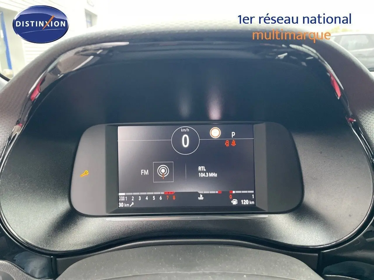 Tableau de bord numérique de l'Opel Corsa blanc 2022, affichant vitesse à 0 km/h et radio RTL 104.3 MHz.