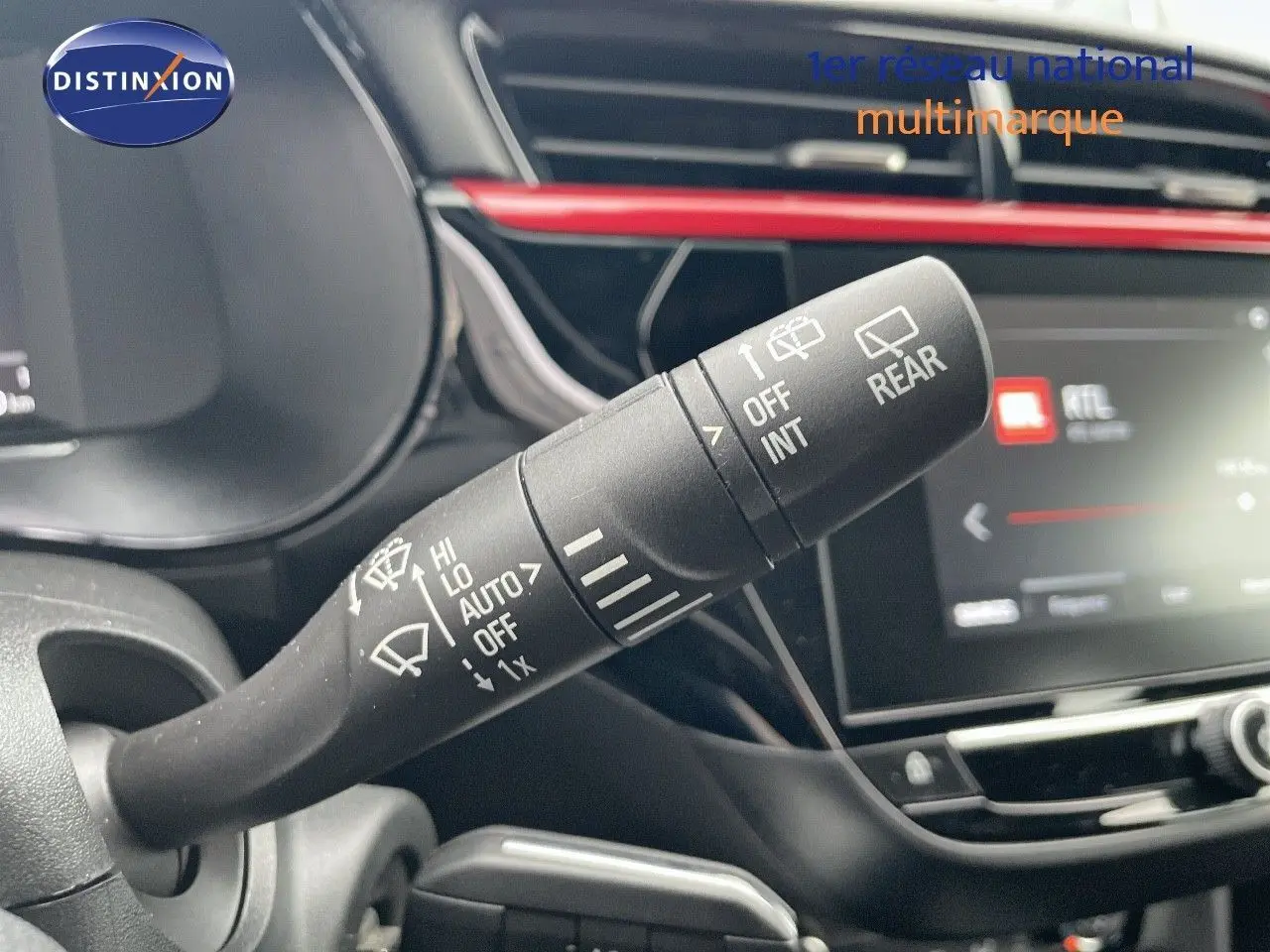 Gros plan sur la commande d'essuie-glace à gauche du volant dans l'habitacle noir et rouge d'une Opel Corsa blanche 2022.