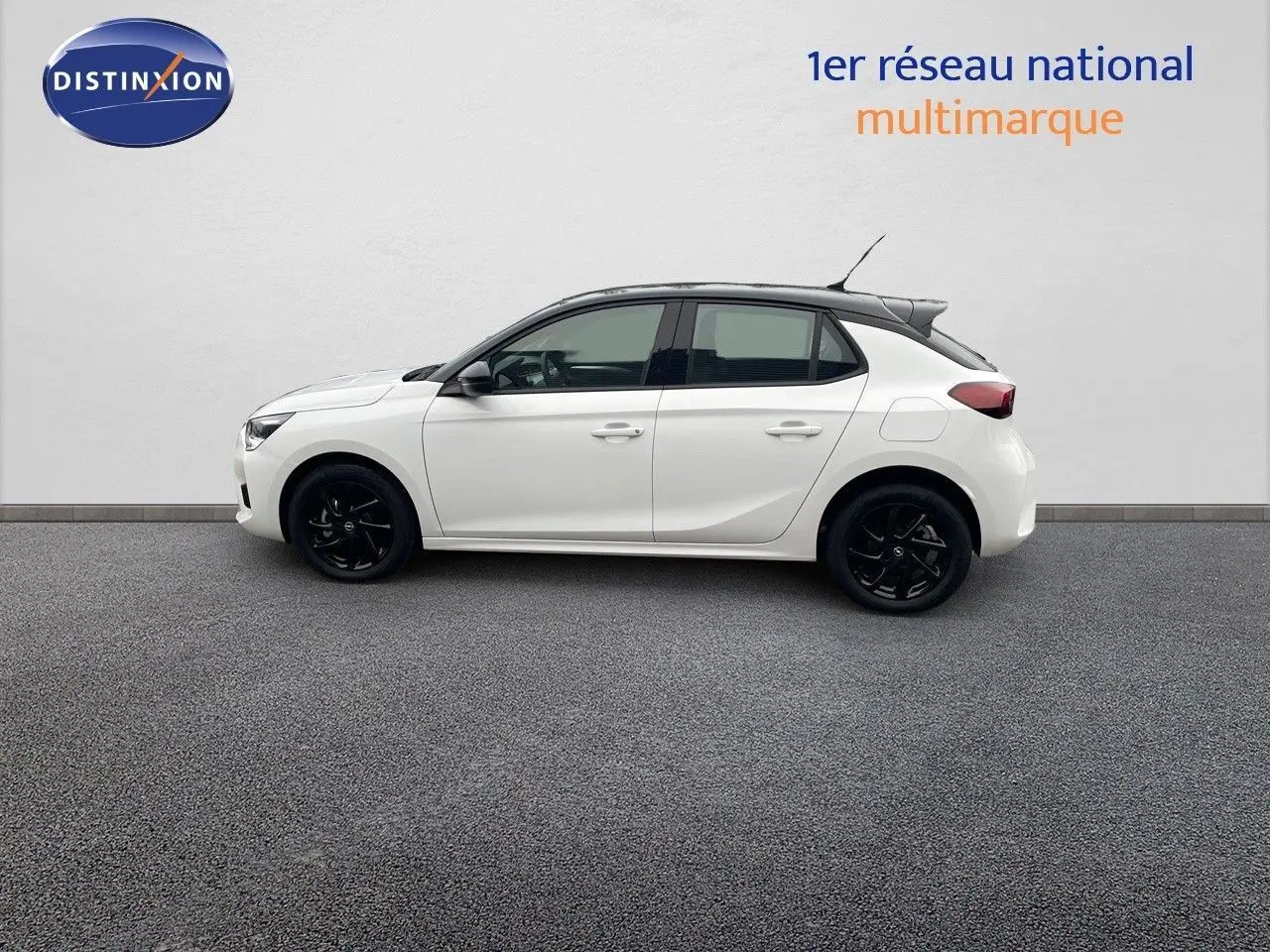 Profil droit d'une Opel Corsa blanche 2022 avec toit noir et jantes noires, sur fond neutre intérieur.