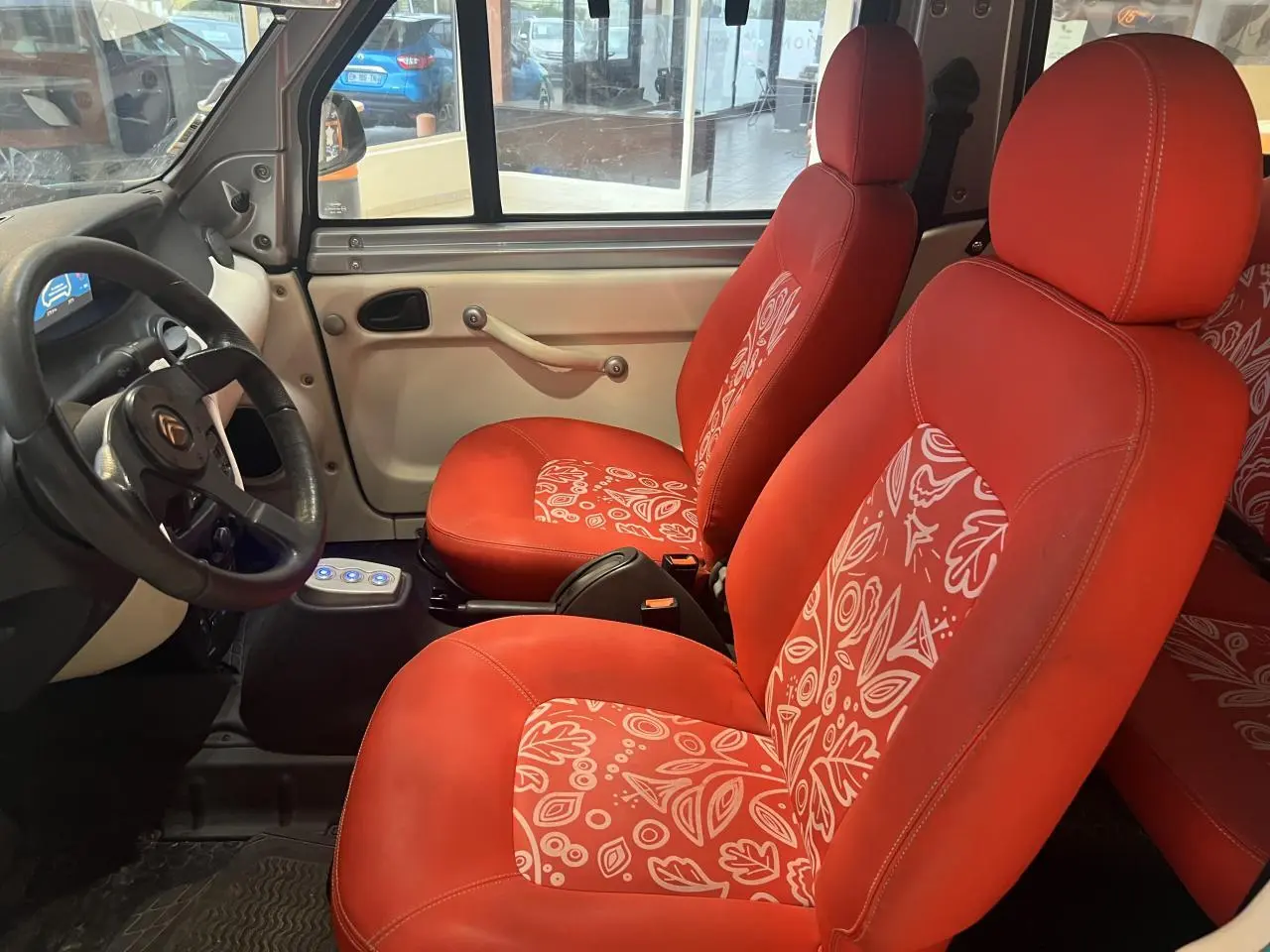 Intérieur avant du Citroën E-MEHARI cabriolet 2016, sièges rouges à motifs blancs et tableau de bord beige.