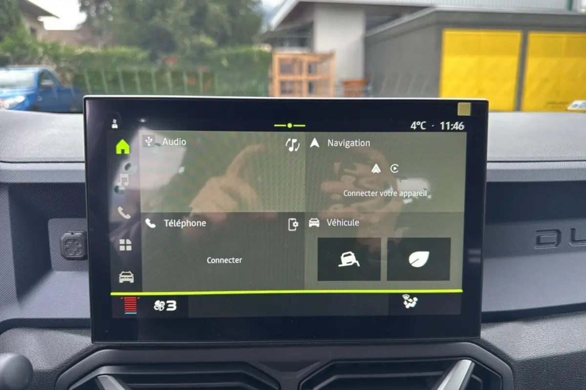 Écran tactile central du tableau de bord du Dacia Duster 2025 gris schiste, affichant les menus audio, navigation et véhicule.