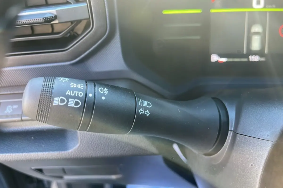 Gros plan sur la commande des phares du tableau de bord du Dacia Duster gris schiste 2025 MILD HYBRID 130 4X4.