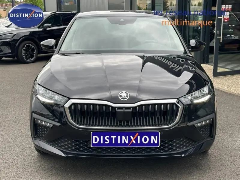 Vue avant d'une Skoda Scala 1.0 TSI Evo2 noir Magic nacré avec calandre chromée et phares LED allumés.